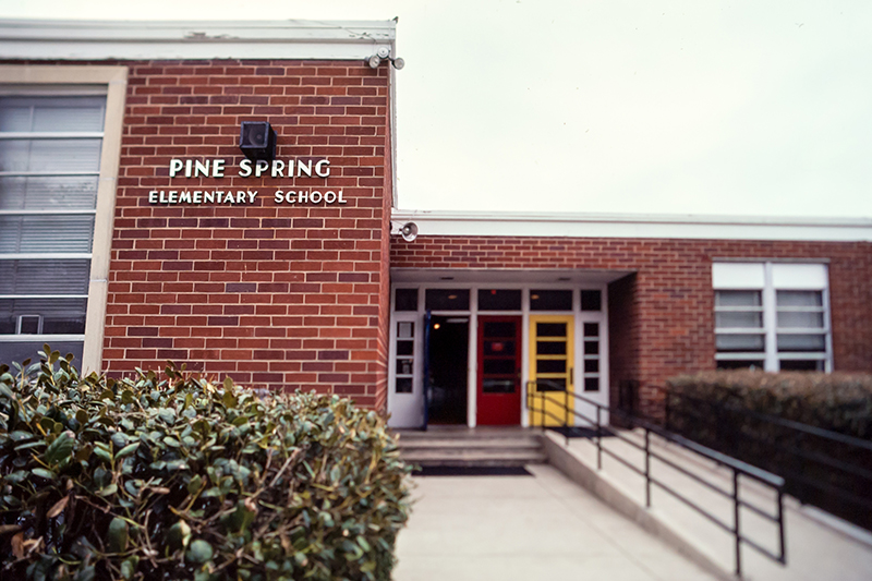 Undated color photograph of Pine Spring Elementary School's main entrance. The front doors are painted white, blue, red, and yellow.